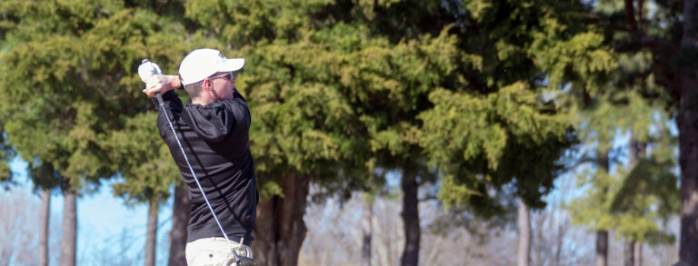 Cadet swinging golf club during tournament.
