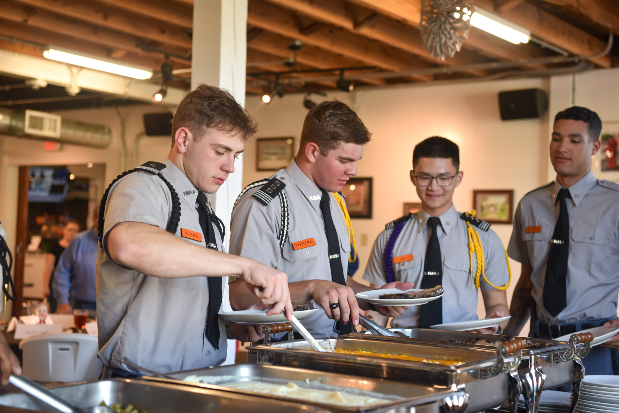 Three cadets serving themselves food at senior dinner.