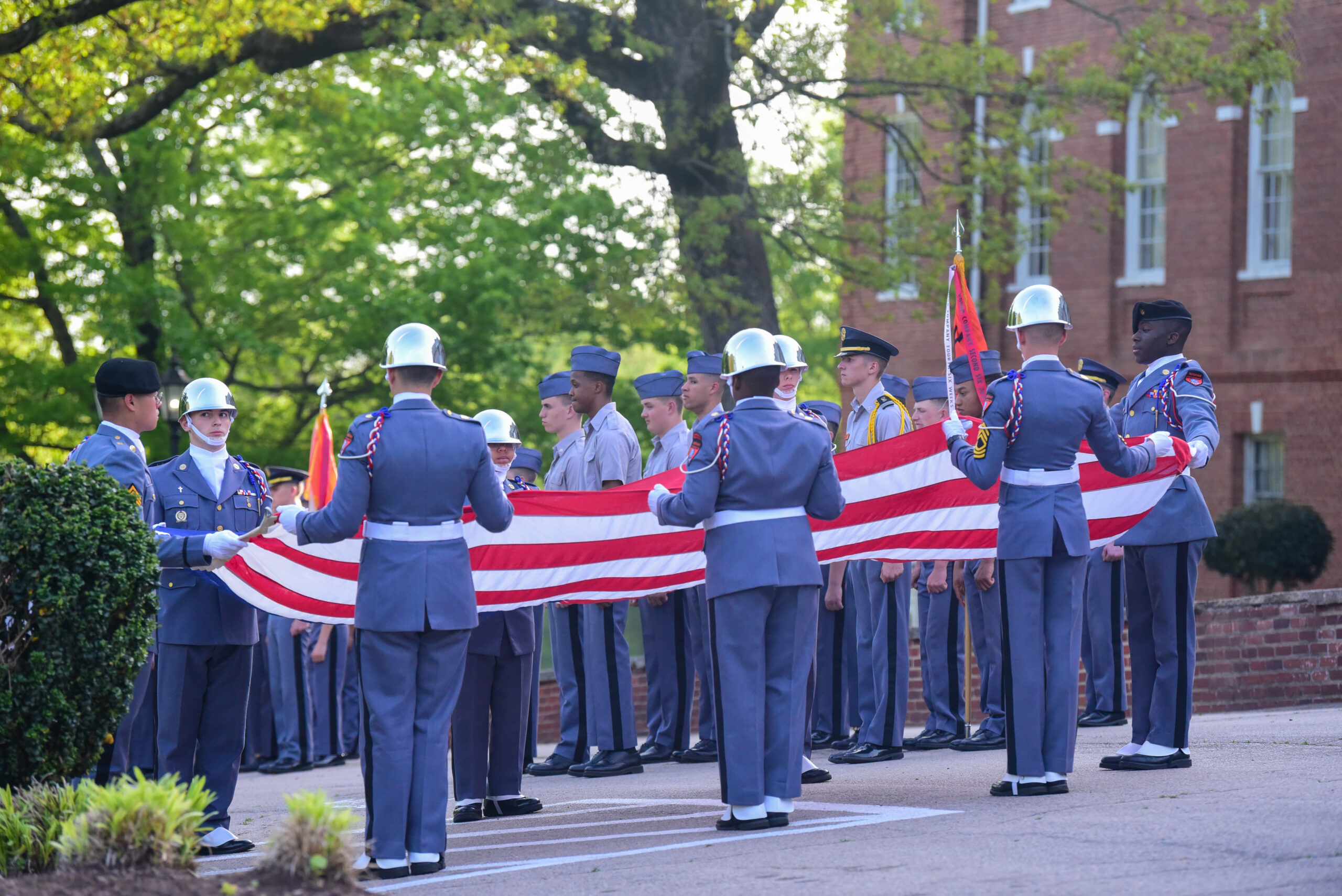 Group of cadets folding the American flag outside.